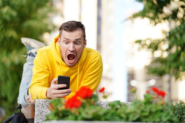 The young man was lying on his stomach outside on a bench with a phone in his hands and in shock at what he saw on the smartphone screen