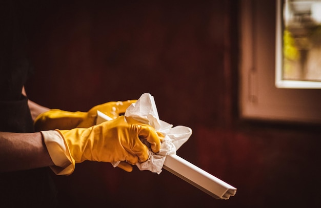 A young man washes window frames with a paper napkin