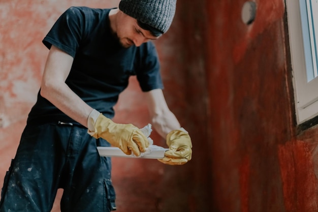 A young man washes window frames with a paper napkin