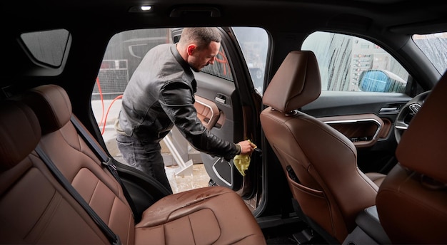 Young man washing car on carwash station outdoor