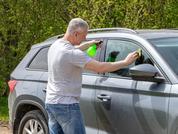 Young man washing the car with a sponge