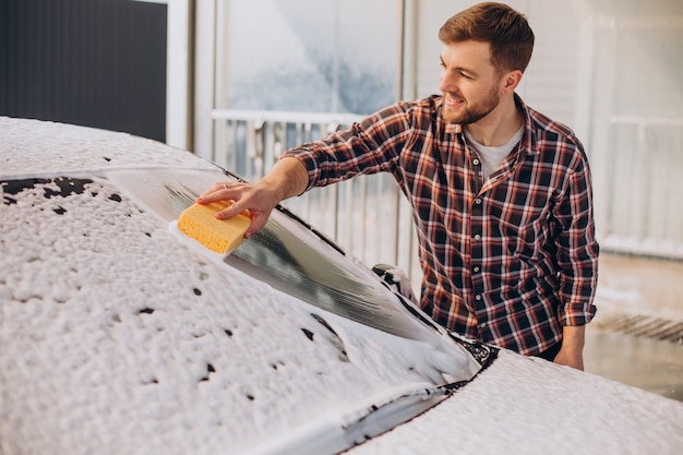 Young man washing his car at carwash