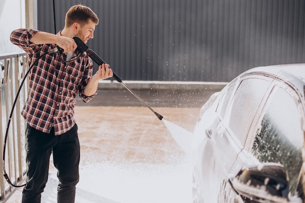 Carwash에서 그의 차를 세척하는 젊은 남자