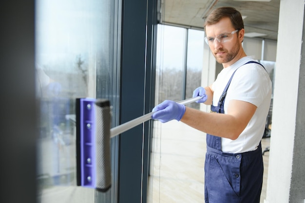 Young man washing window in office