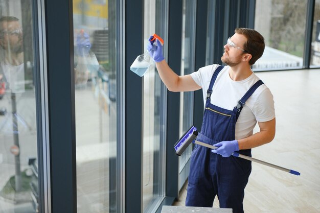 Young man washing window in office