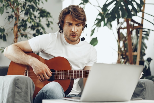 young man watching guitar tutorial on his laptop