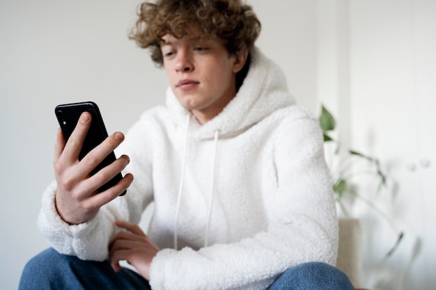 Photo young man watching a movie using his smartphone while sitting on a chair