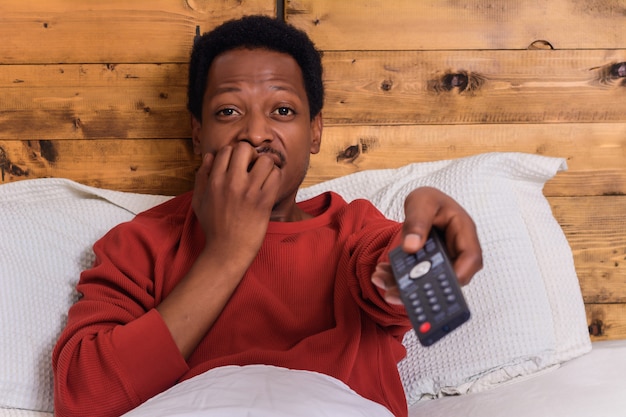 Photo young man watching tv on bed at home.