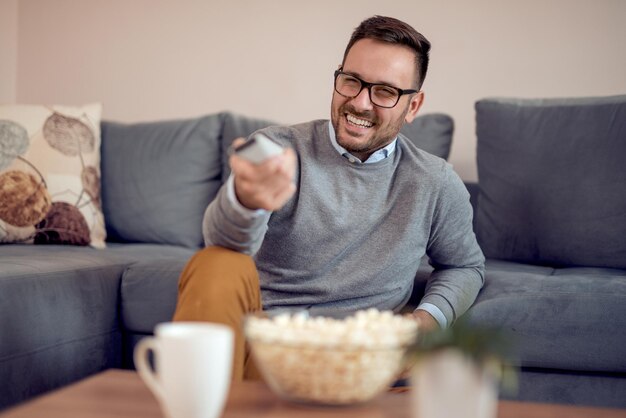 自宅のソファでテレビを見ている若い男性