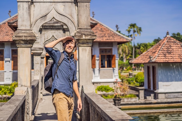 Young man in Water Palace Soekasada Taman Ujung Ruins on Bali Island in Indonesia Amazing old architecture Travel and holidays background