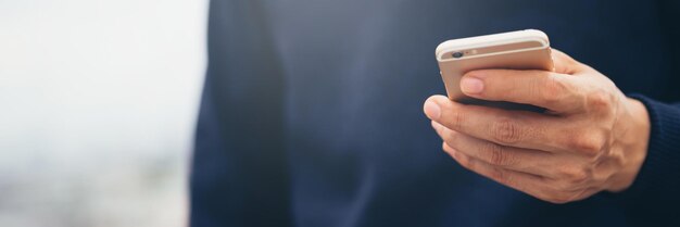 Young man wear plaid shirt close up hand using on cell phone during rest on sofa sitting in watching message on mobile smart phone during break relax soft focus