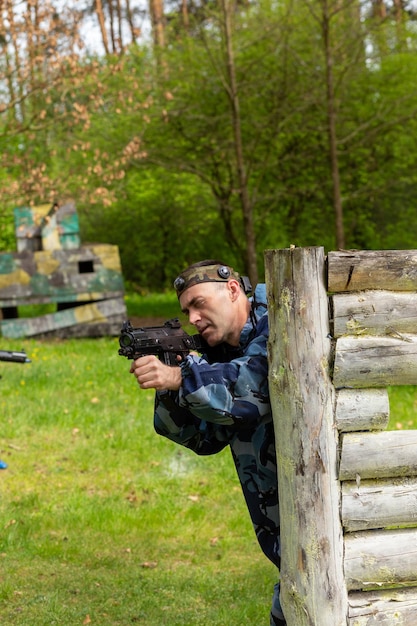 Young man weared in camouflage playing laser tag in special forest playground