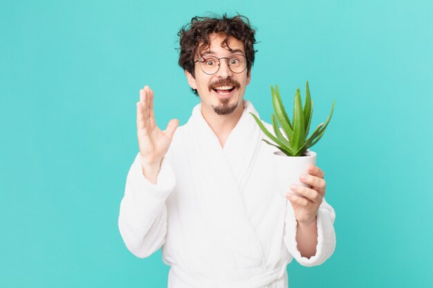 Young man wearing bathrobe feeling happy and astonished at something unbelievable