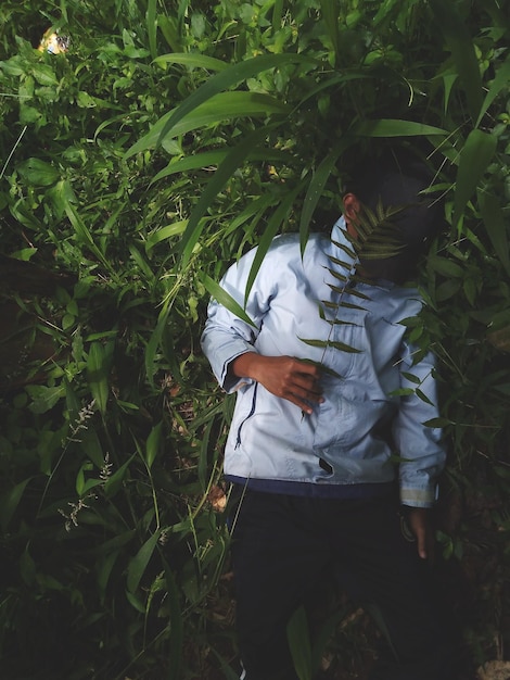 Photo a young man wearing blue clothes posing in the forest that is one with nature