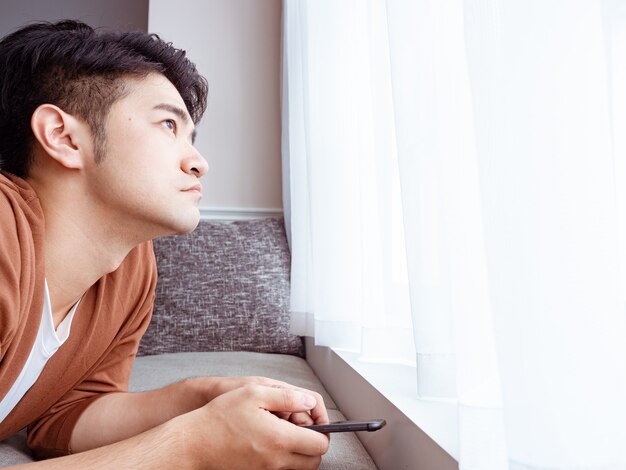 Young man wearing casual clothes and using smartphone at home