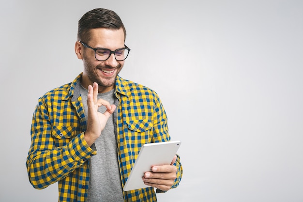 Giovane che indossa una camicia casual e occhiali da vista utilizzando una tavoletta