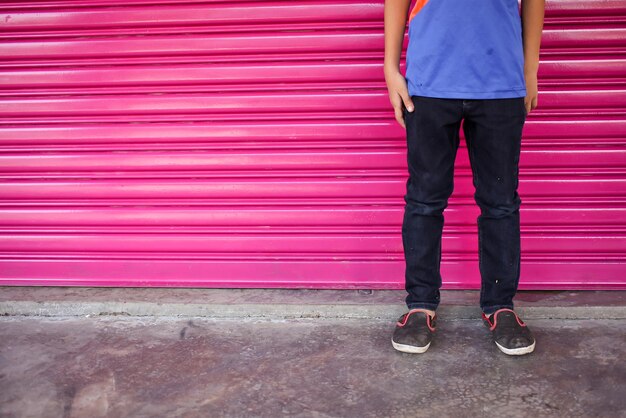 Young man wearing a check shirt and jeans against a wall