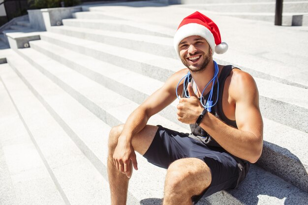 外で運動するクリスマスの帽子をかぶって若い男