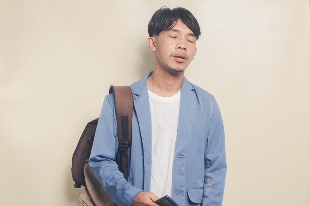 Young man wearing college suit carrying phone and backpack on\
isolated background