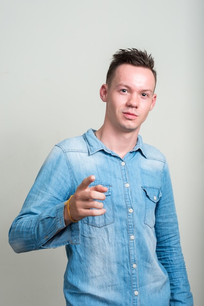 young man wearing denim shirt against white space