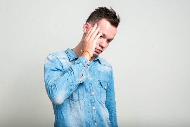 young man wearing denim shirt against white space