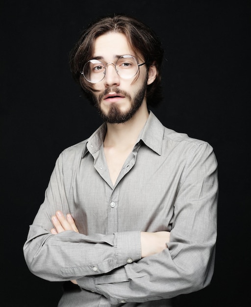 Young man wearing eyeglasses over black background