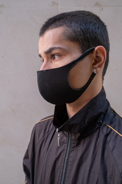 Giovane che indossa una maschera facciale che guarda lateralmente durante la pandemia.