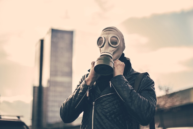 Young man wearing a gas mask on a city street