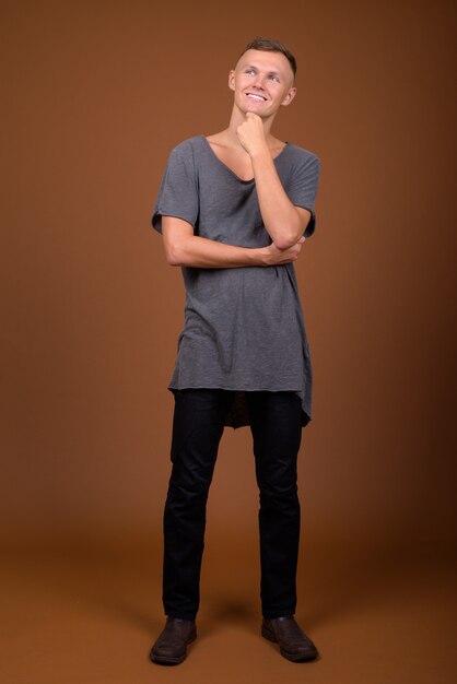 Young man wearing gray shirt against brown background