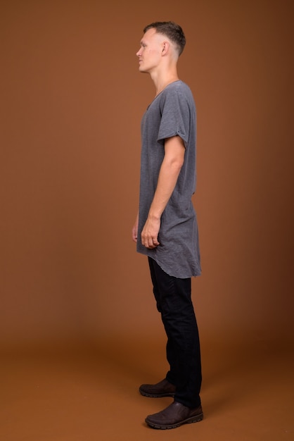 Photo young man wearing gray shirt against brown background