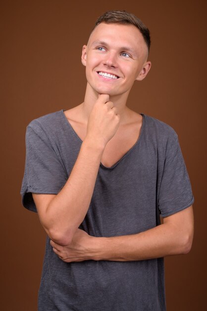 Young man wearing gray shirt against brown background