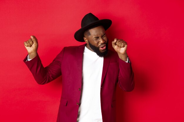 Young man wearing hat against red background