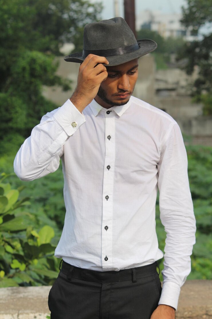 Photo young man wearing hat looking down while standing outdoors