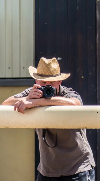 写真 レールに立ってカメラで写真を撮る帽子をかぶった若い男性