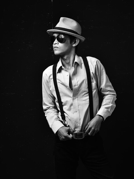 Young man wearing hat standing against black background