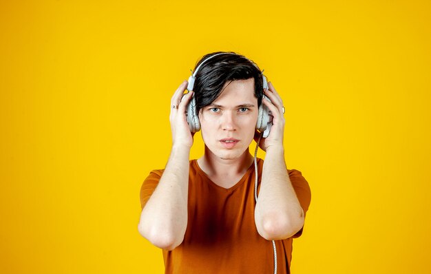 Young man wearing headphones and enjoying music; on a background of yellow gold, the emotions of a young man