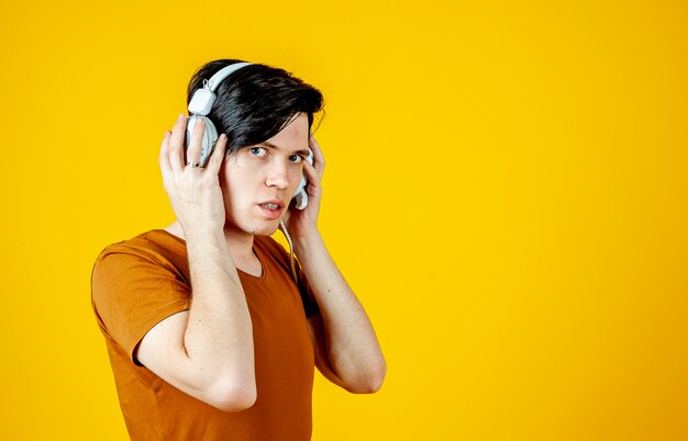 Young man wearing headphones and enjoying music; on a background of yellow gold, the emotions of a young man