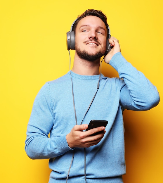 Young man wearing headphones and holding mobile phone