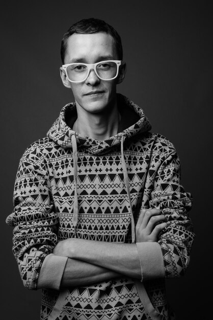  young man wearing hoodie against gray wall in black and white