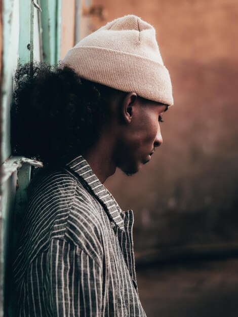 Photo young man wearing knit hat by wall