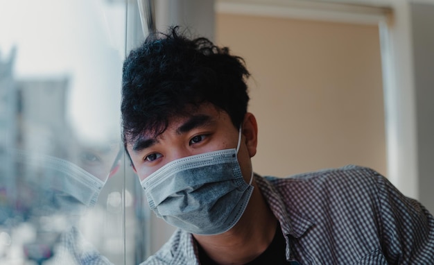 Young man wearing mask by window at home