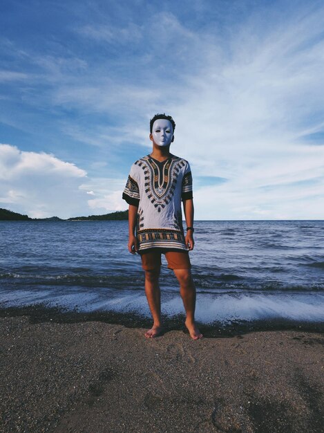 사진 해변 에 서 있는 젊은 남자 가 마스크 를 착용 하고 있다