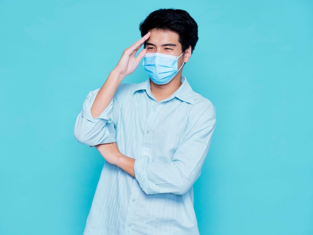 Young man wearing medical mask while holding his head. Virus protection