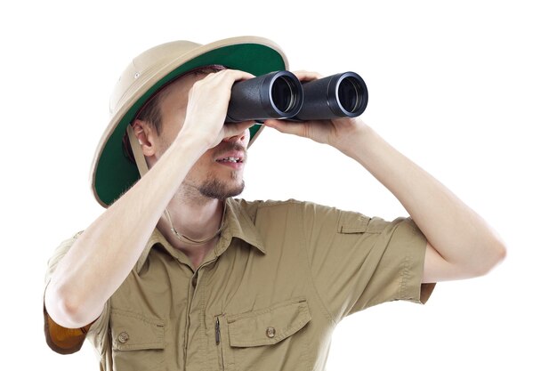 Young man wearing pith helmet looking through binoculars isolated on white