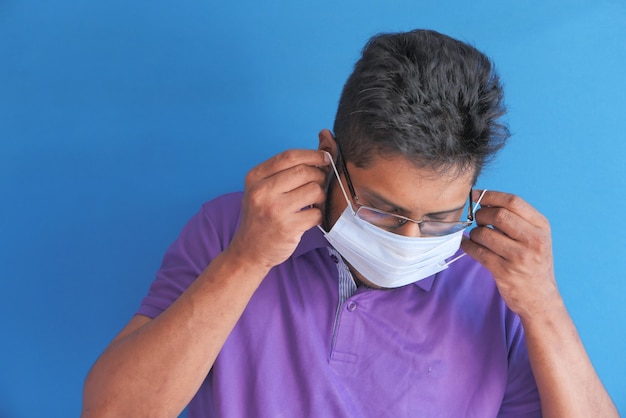 Young man wearing protective face mask on blue wall