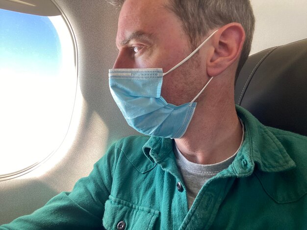 A young man wearing a protective mask on an airplane flight