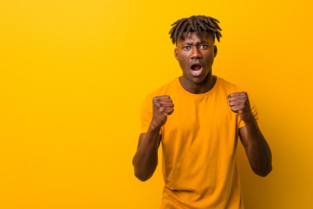 Young man wearing rastas over yellow background cheering carefree and excited. Victory concept.