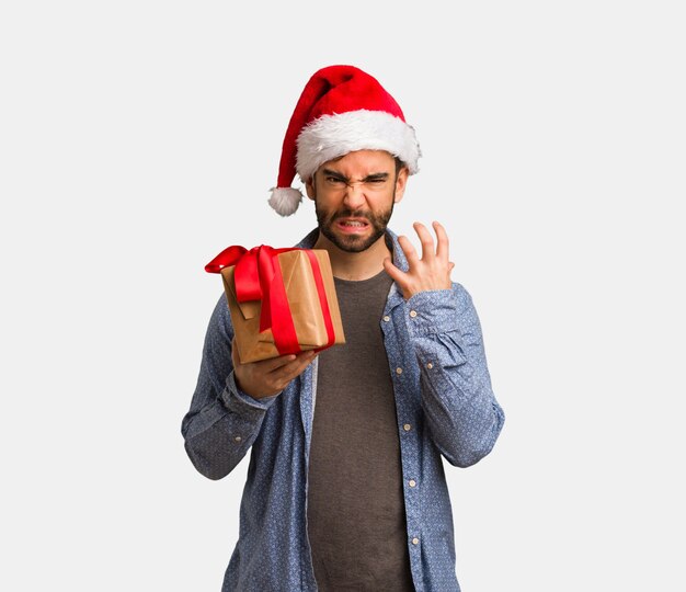 Young man wearing santa hat angry and upset