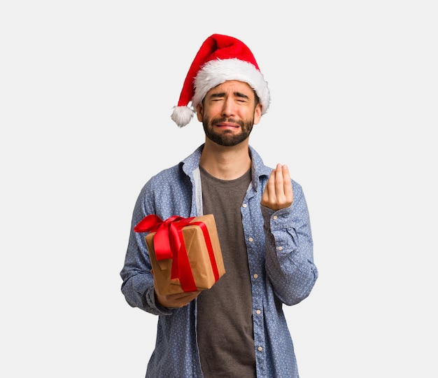 Young man wearing santa hat doing a gesture of need