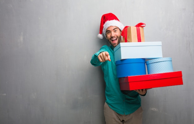 Giovane che porta i regali della tenuta del cappello di santa allegri e sorridenti